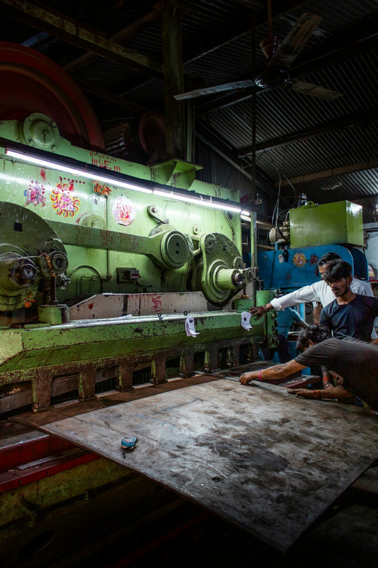 Workers operating heavy machinery in a factory.