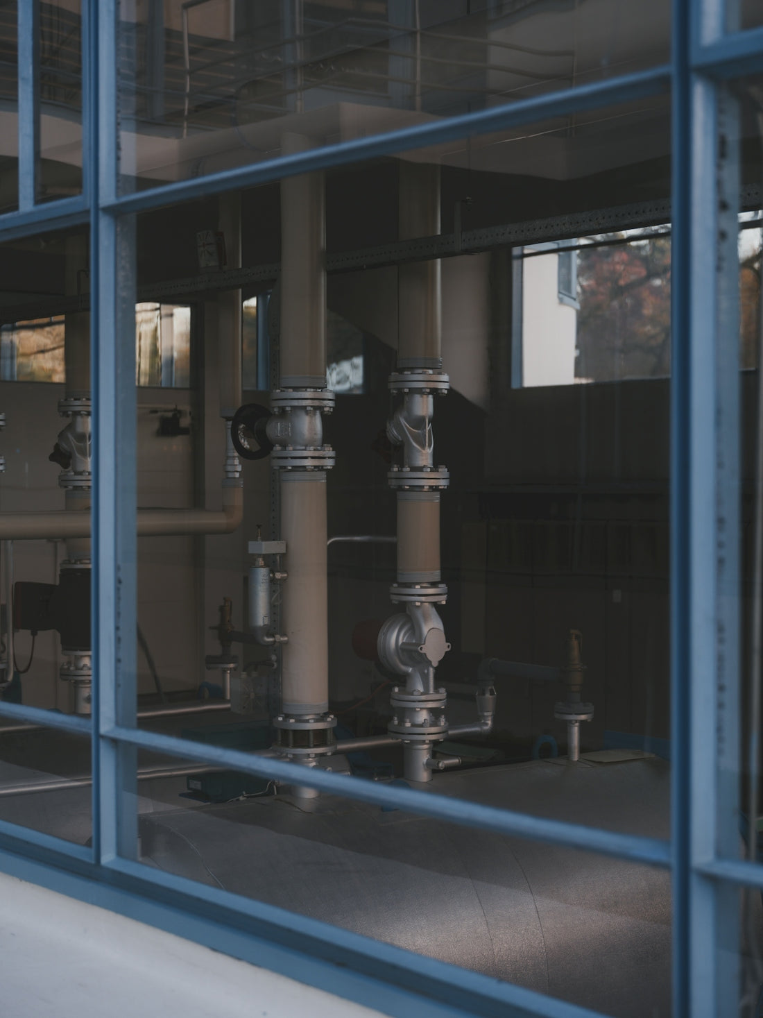 Industrial pipes and machinery seen through glass