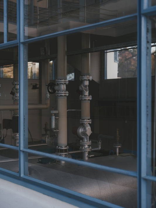 Industrial pipes and machinery seen through glass