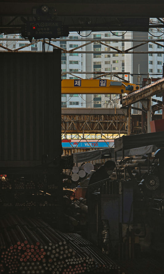 Industrial setting with stacked metal rods and a crane.