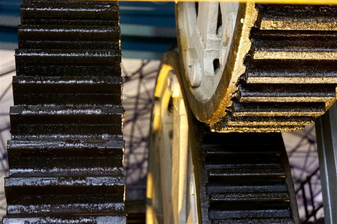 Two large, greasy gears meshed together in machinery.